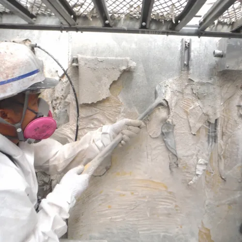 壁の劣化材を除去する作業員