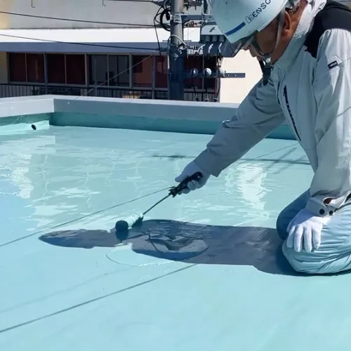 屋上でローラー防水塗装作業中