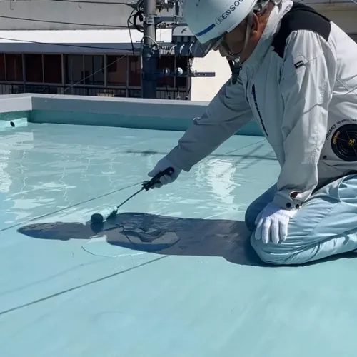 屋上で防水塗装を行う作業員